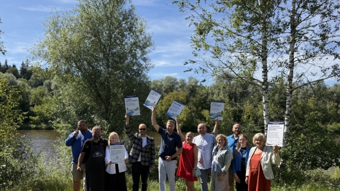 cilvēki pie Gaujas ar diplomiem rokās