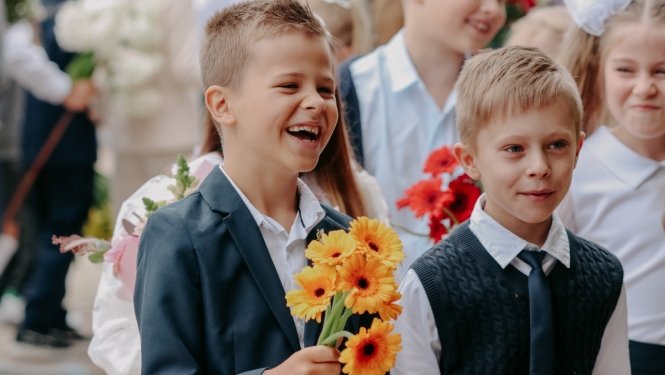 Zinību diena - smaidīgi skolēni ar ziediem rokās