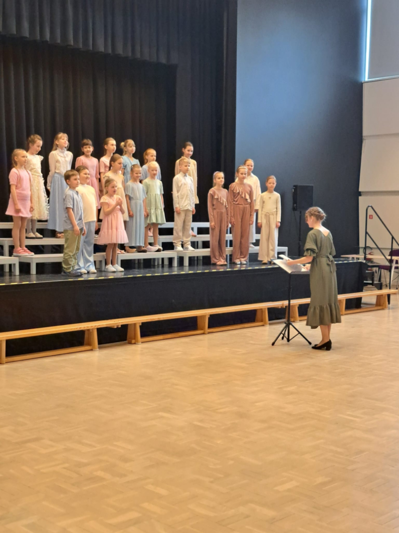 Bērni dzied diriģentes pavadībā