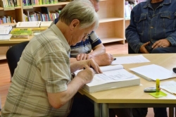 Komponists Gunārs Freidenfelds atstāj savu veltījumu Latvijas 100. dzimšanas dienas Tautas Saimes grāmatā.