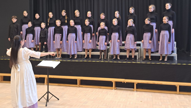 Bērni dzied diriģentes pavadībā