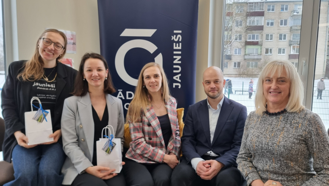 Pieci cilvēki sēž uz dīvana, fonā jaunišu centra logo