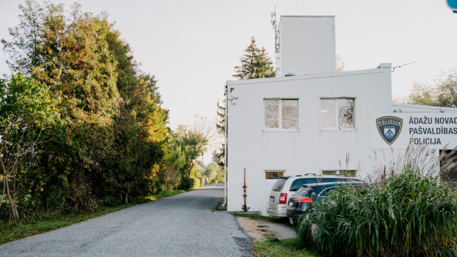 Ādažu novada pašvaldības policijas ēka, baltā krāsā, zaļojošu koku ieskauta