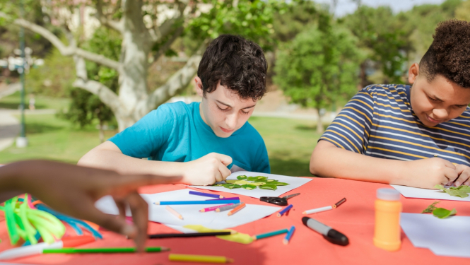 jaunieši pie galda zīmē