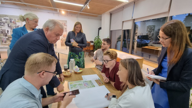 vairaki cilvēki ap galdu, notiek diskusija