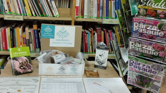 grāmatu galds, uz kura atrodas arī augu un dārzeņu sēklas