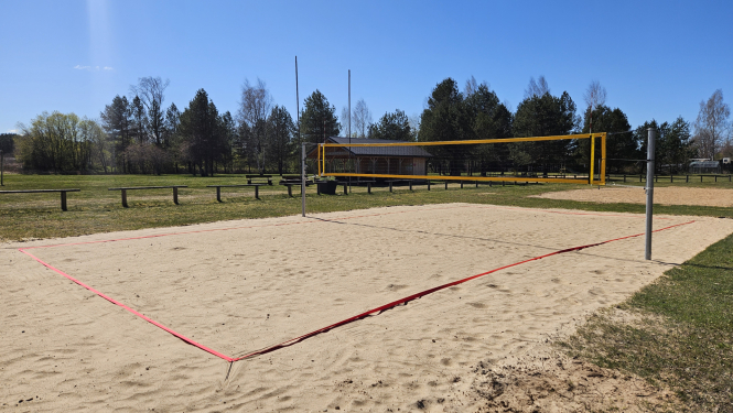 Pludmales volejbola laukums, tīkls, smiltis, līnijas, zilas debesis