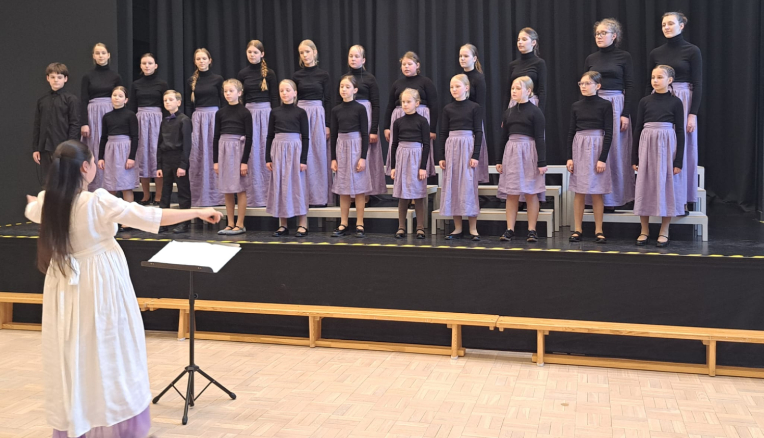 Bērni dzied diriģentes pavadībā