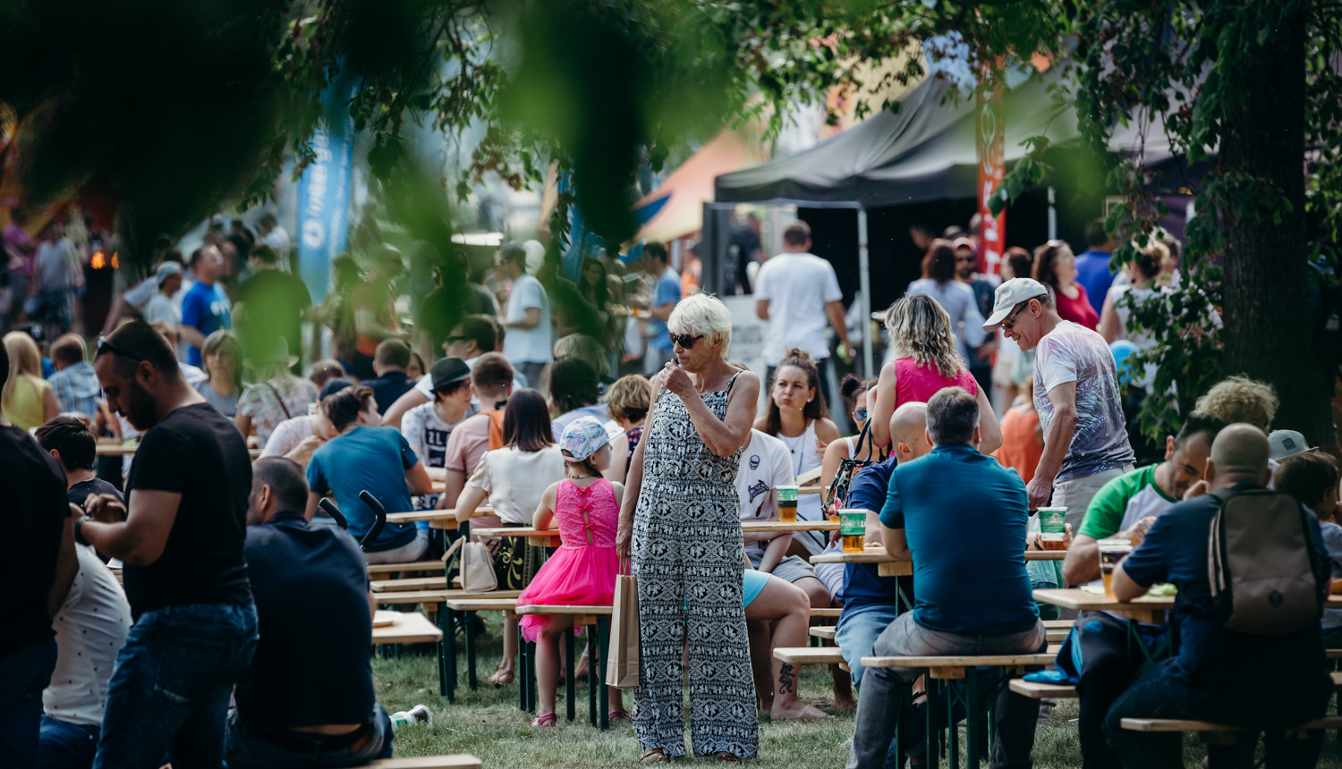 Cilvēki sēž pie galdiņiem un ēd