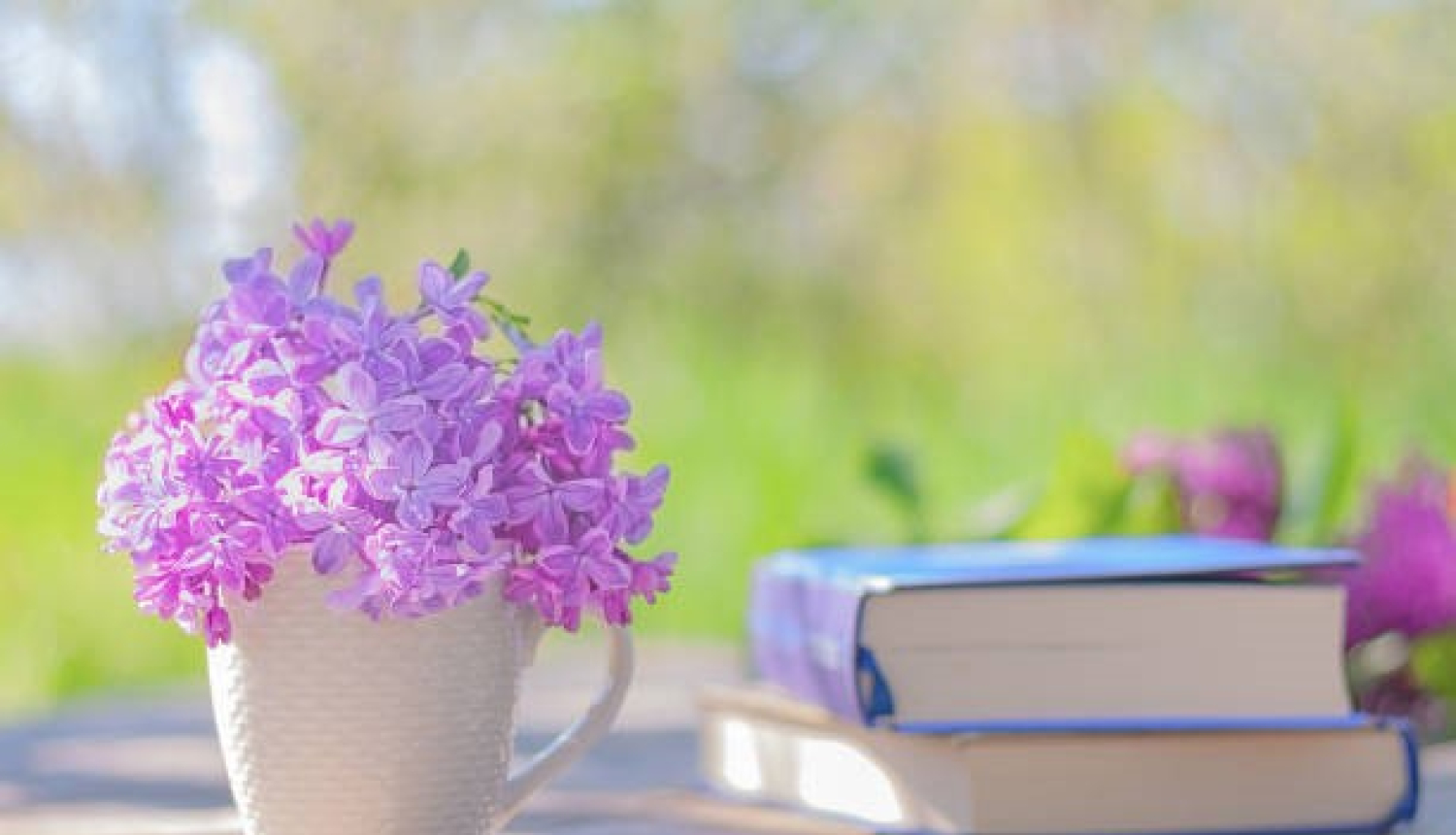 ziedošas puķes vāzē un grāmata uz galda