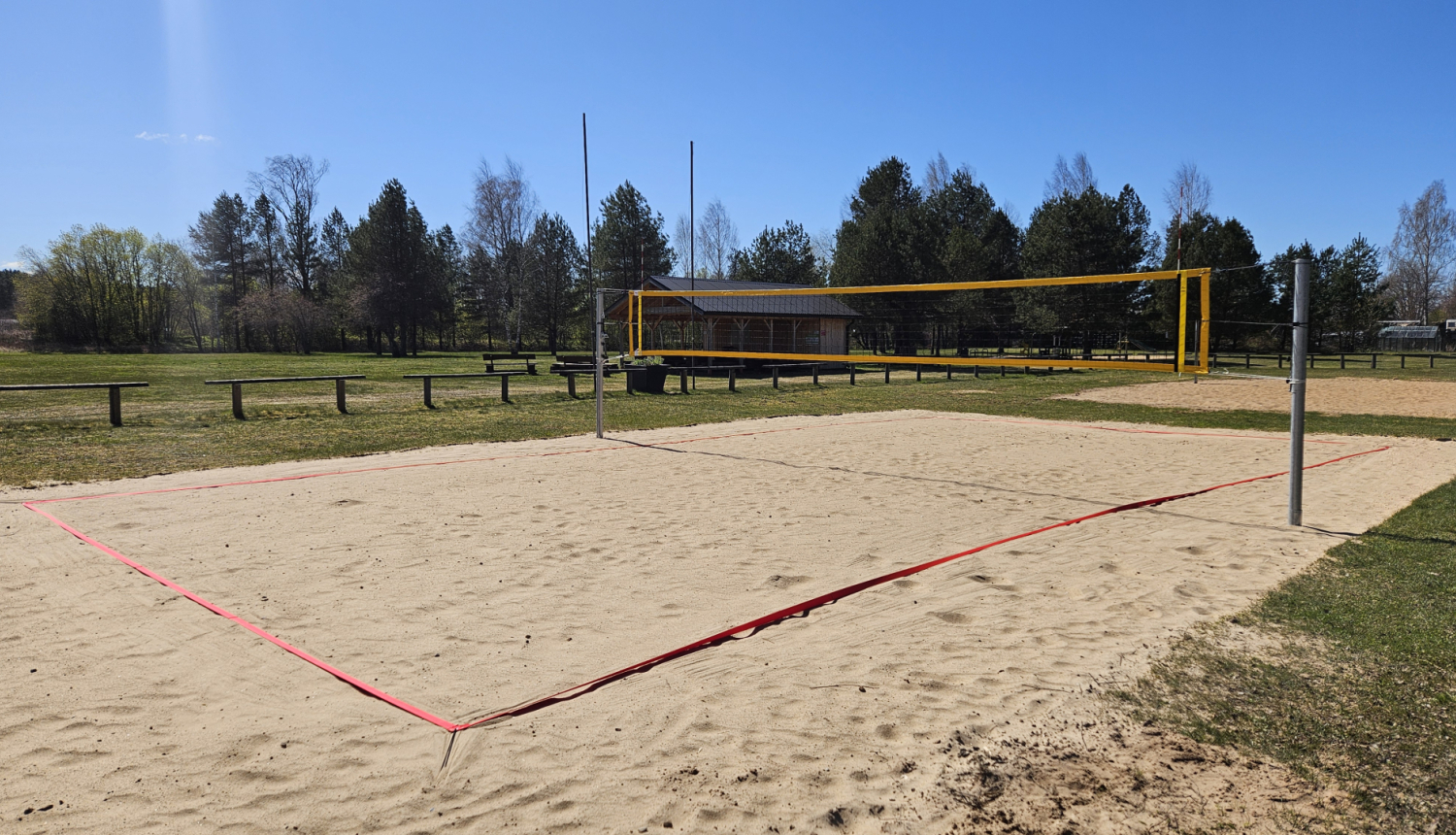 Pludmales volejbola laukums, tīkls, smiltis, līnijas, zilas debesis
